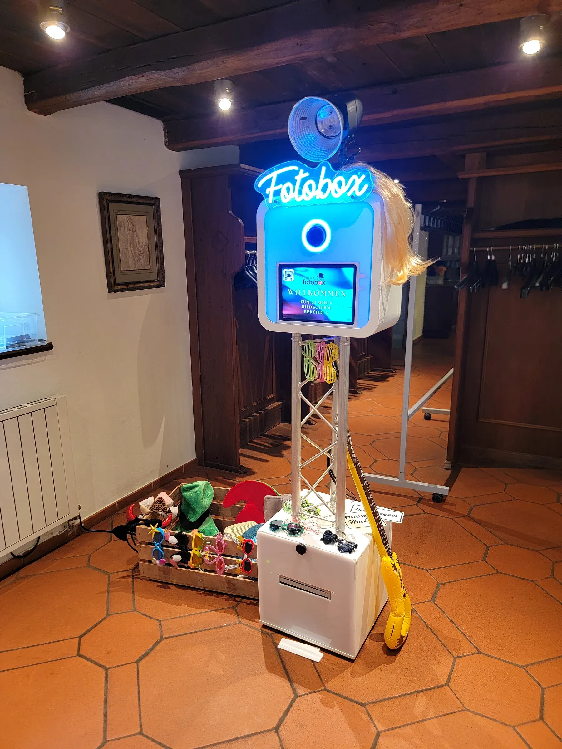 Fotobox mieten Bielefeld für die Hochzeit: Fotobox mit Neon-Logo, Requisiten und Drucker in einer rustikalen Location